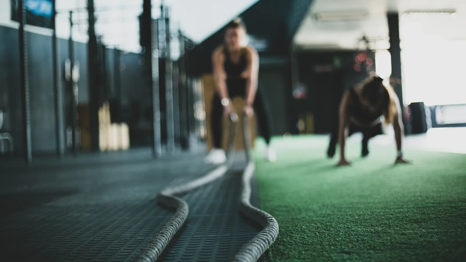Functional-fitness athletes training indoors with battle ropes and floor work